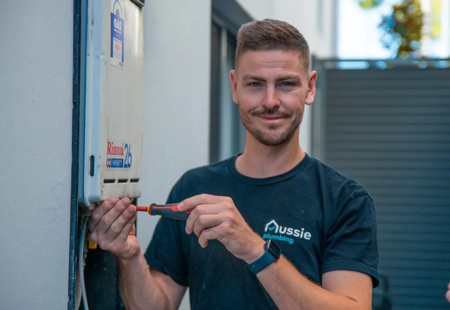 An Aussie Plumbing technician working on a gas hot water unit