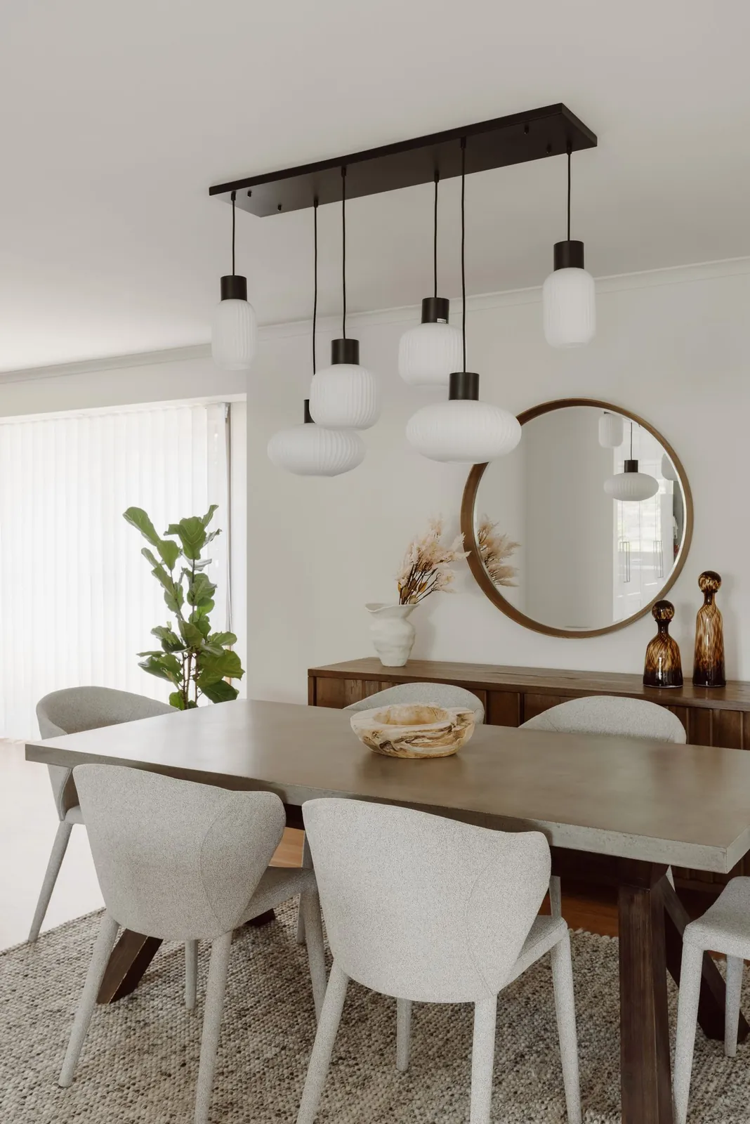 Contemporary Bliss dining room with ribbed glass pendants, a round timber mirror and soft grey chairs